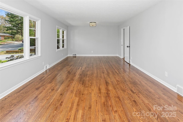 unfurnished room featuring visible vents, baseboards, and wood finished floors