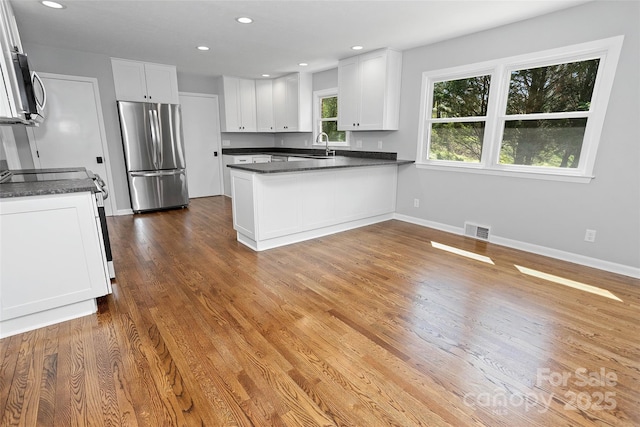 kitchen with dark countertops, visible vents, appliances with stainless steel finishes, and a peninsula