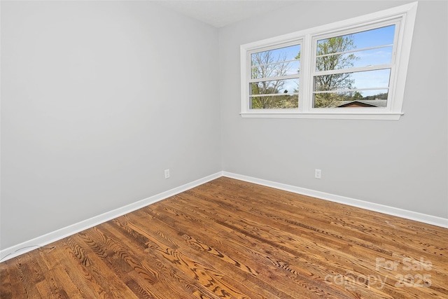 spare room featuring dark wood-type flooring and baseboards