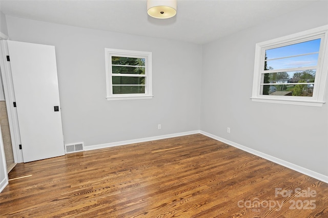 spare room with wood finished floors, baseboards, and visible vents