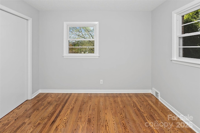 spare room with visible vents, baseboards, and wood finished floors
