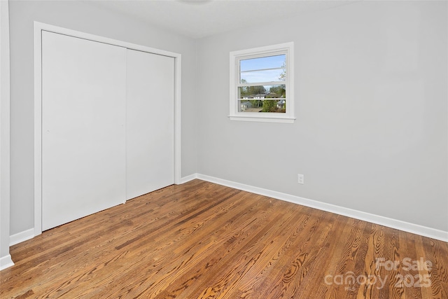 unfurnished bedroom featuring a closet, baseboards, and wood finished floors