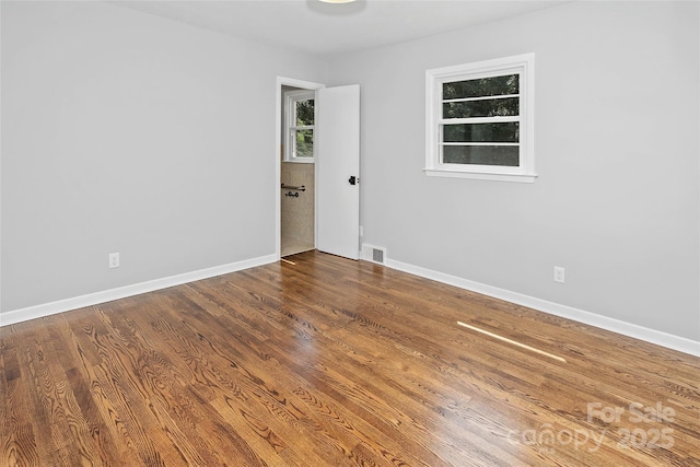 empty room with visible vents, baseboards, and wood finished floors