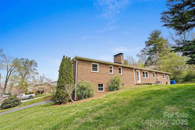 back of property with a yard, brick siding, and a chimney