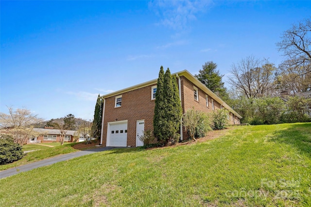 view of property exterior featuring brick siding, a yard, a garage, and aphalt driveway