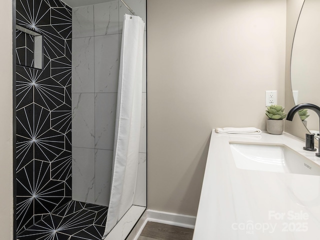 bathroom featuring a shower with shower curtain, a sink, and baseboards