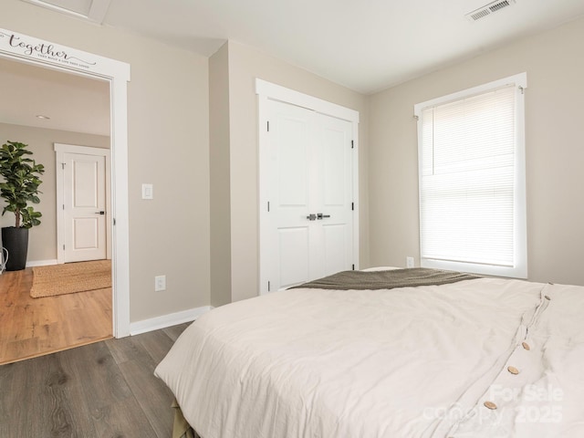 bedroom featuring dark wood-style flooring, baseboards, and a closet