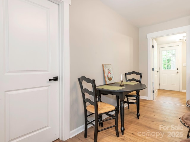 dining space with light wood-type flooring and baseboards