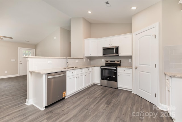 115 Frances St, Salisbury, NC 28147 - kitchen with appliances with stainless steel finishes, vaulted ceiling, dark wood finished floors, white cabinetry, and backsplash