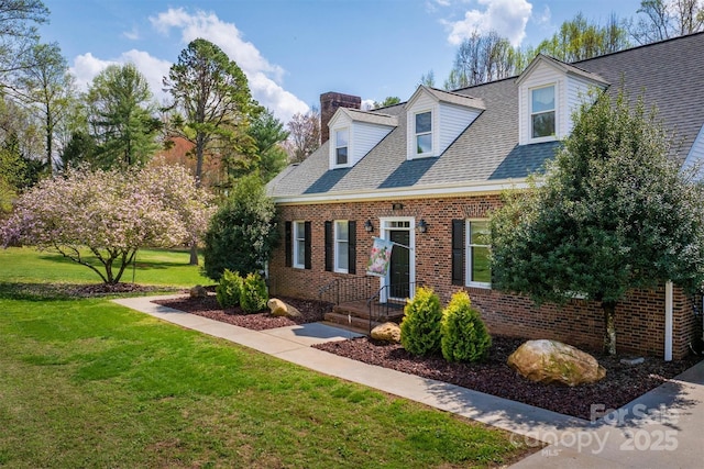 cape cod house featuring brick siding, a front lawn, a shingled roof, and a chimney