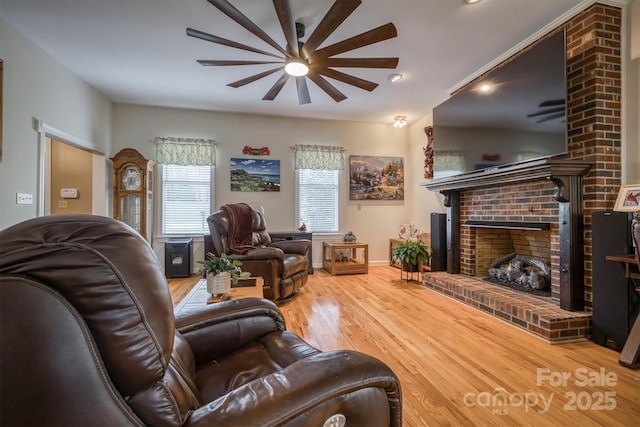 living room featuring wood finished floors, ceiling fan, a fireplace, and baseboards