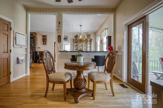 dining room with visible vents, baseboards, plenty of natural light, light wood-type flooring, and wallpapered walls