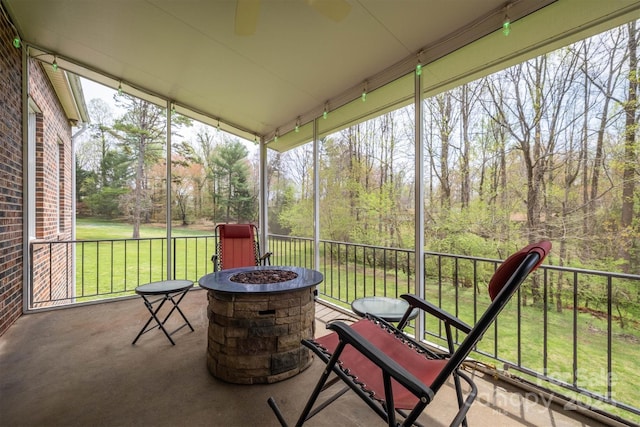 sunroom / solarium featuring a ceiling fan, an outdoor fire pit, and a healthy amount of sunlight