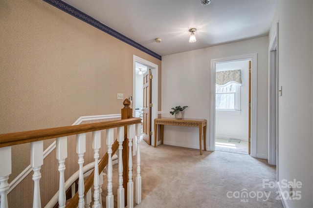 hallway featuring light carpet and baseboards