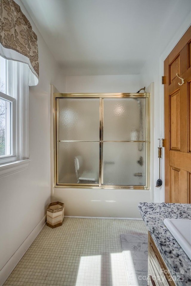 full bathroom featuring vanity, baseboards, and combined bath / shower with glass door