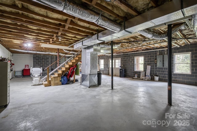 basement featuring electric panel, stairs, and a wealth of natural light