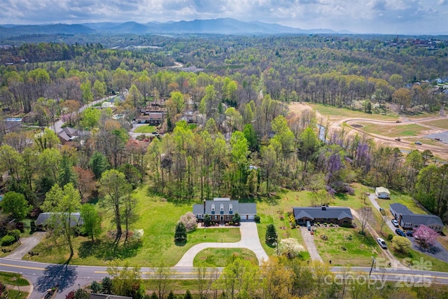 drone / aerial view featuring a wooded view and a mountain view