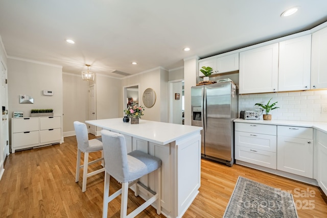3510 Conway Ave, Charlotte, NC 28209 - kitchen with stainless steel fridge, crown molding, a kitchen bar, backsplash, and light wood finished floors