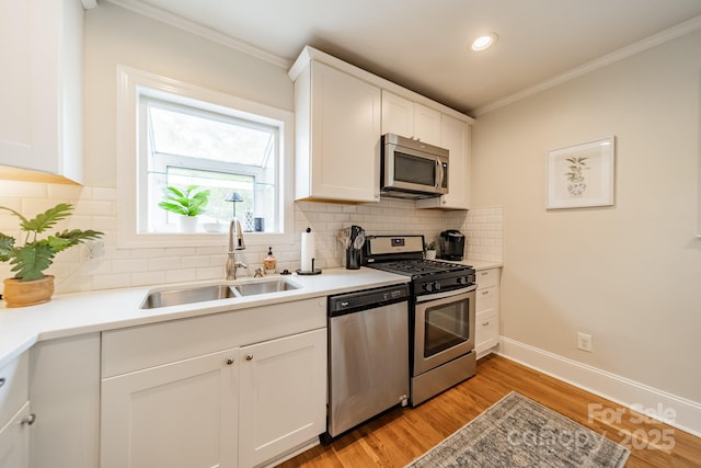 3510 Conway Ave, Charlotte, NC 28209 - kitchen with appliances with stainless steel finishes, a sink, crown molding, white cabinetry, and light wood-style floors
