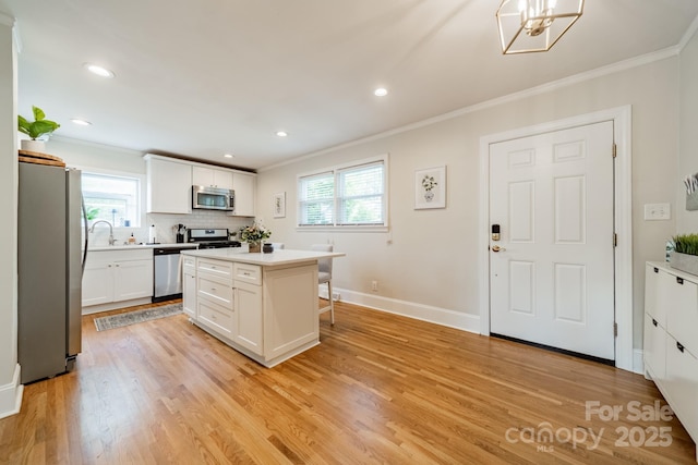 3510 Conway Ave, Charlotte, NC 28209 - kitchen with appliances with stainless steel finishes, crown molding, a breakfast bar area, plenty of natural light, and white cabinets