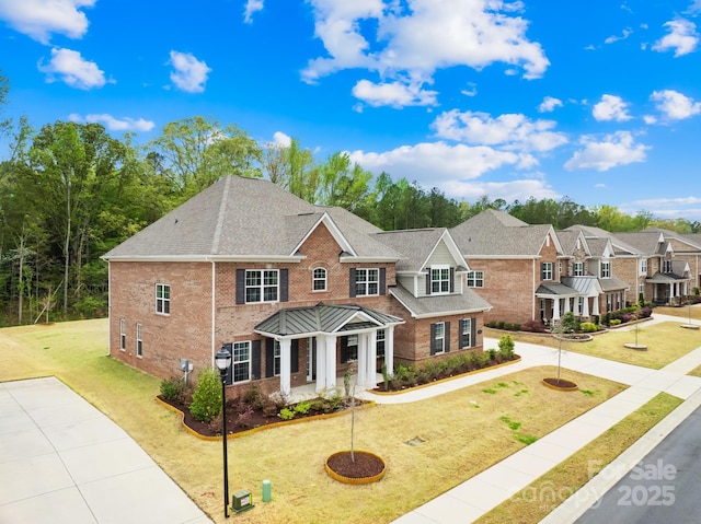 view of front of house with a front yard, brick siding, a shingled roof, and a residential view