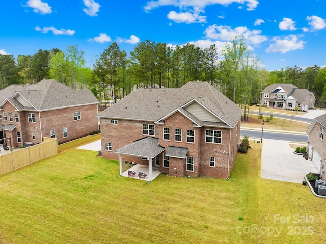 back of house featuring a yard, a patio area, fence, and brick siding
