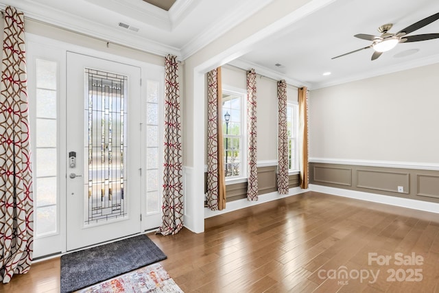entrance foyer with crown molding, visible vents, ceiling fan, and wood finished floors