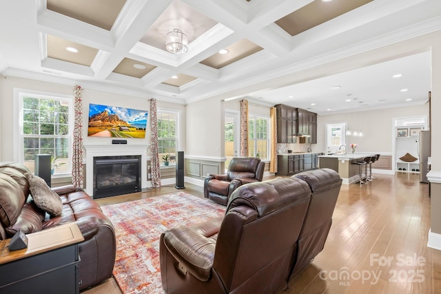 living room with a wealth of natural light, ornamental molding, beam ceiling, and coffered ceiling