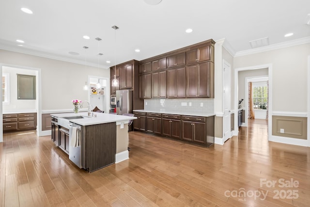 kitchen featuring a sink, dark brown cabinets, appliances with stainless steel finishes, and crown molding