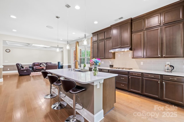 kitchen featuring light countertops, light wood-style floors, decorative backsplash, and a sink