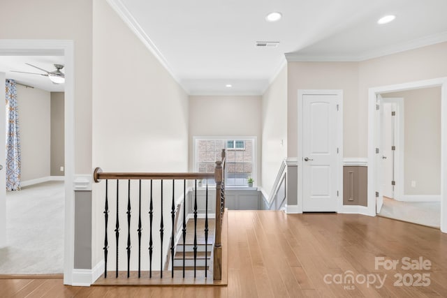 corridor with crown molding, visible vents, an upstairs landing, and wood finished floors