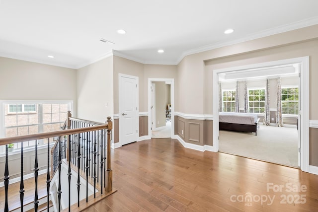 hallway with visible vents, crown molding, and wood finished floors