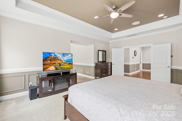 carpeted bedroom with crown molding, a decorative wall, a tray ceiling, visible vents, and recessed lighting