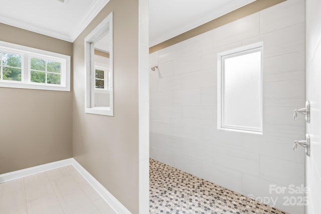 full bath with baseboards, a tile shower, and crown molding