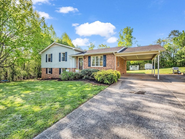 tri-level home with driveway, a front lawn, an attached carport, brick siding, and an outbuilding