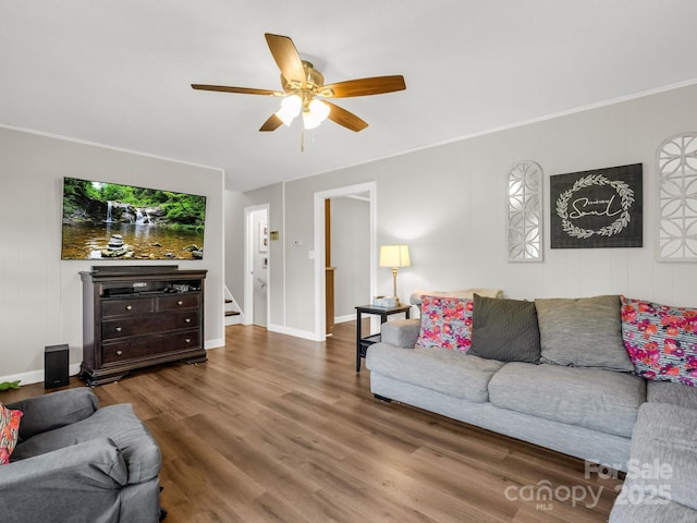 living room featuring wood finished floors, baseboards, a ceiling fan, and stairway