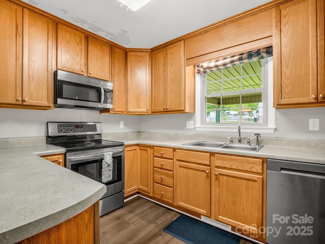 kitchen featuring visible vents, wood finished floors, light countertops, a sink, and stainless steel appliances