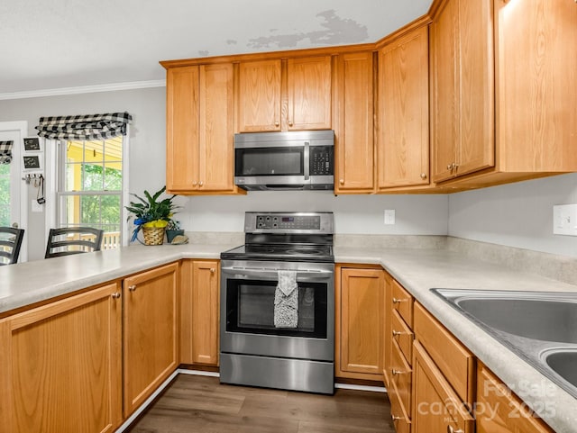 kitchen with dark wood-style flooring, ornamental molding, light countertops, a sink, and stainless steel appliances