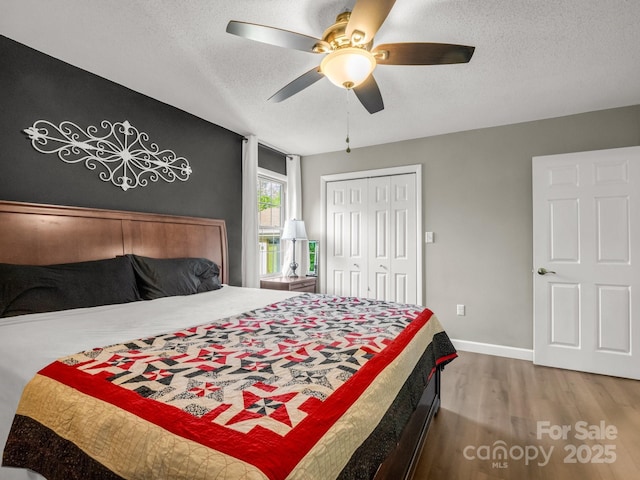 bedroom featuring a closet, baseboards, a textured ceiling, a ceiling fan, and wood finished floors