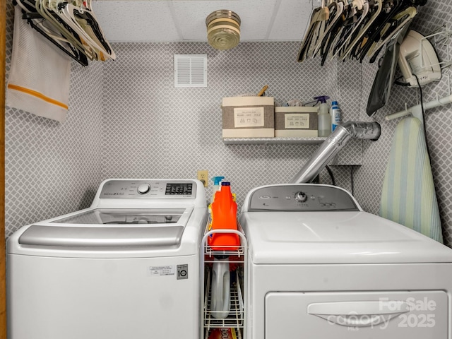laundry area with tile walls, visible vents, washer and clothes dryer, and laundry area