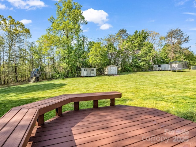 wooden terrace featuring an outdoor structure, a playground, a lawn, and a storage unit