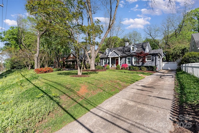 cape cod-style house featuring a front yard and fence