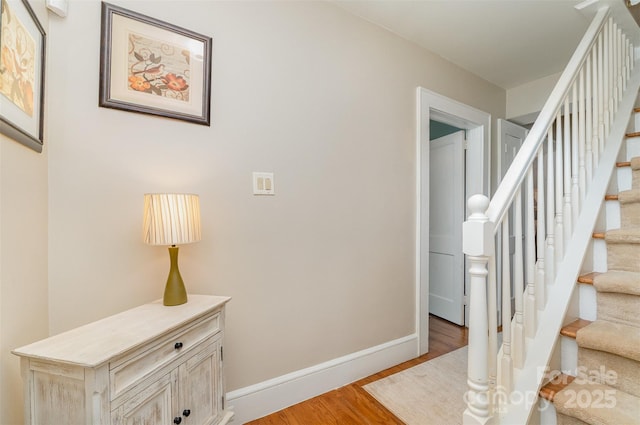 staircase featuring wood finished floors and baseboards