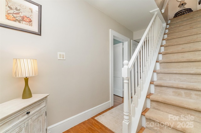 stairway featuring baseboards and wood finished floors