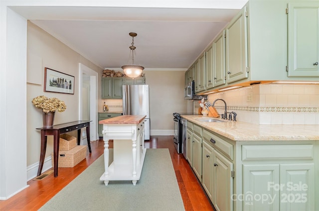 kitchen featuring a sink, ornamental molding, appliances with stainless steel finishes, and dark wood-style floors