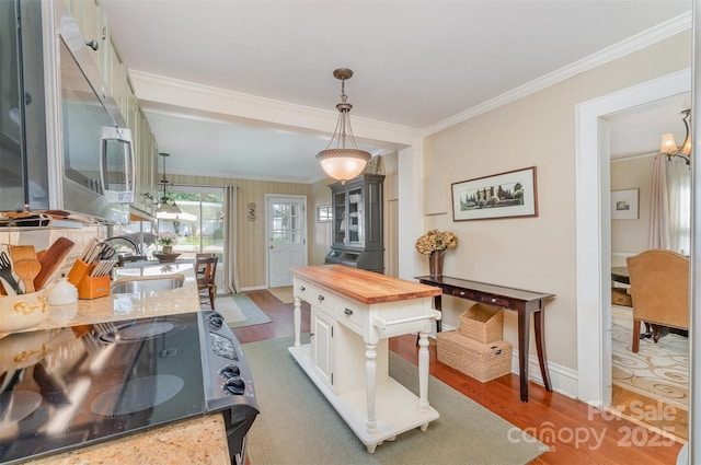 kitchen with stainless steel microwave, wooden counters, black electric range, a sink, and wood finished floors