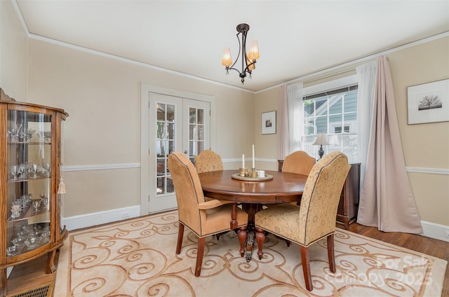 dining room with crown molding, wood finished floors, french doors, a notable chandelier, and baseboards