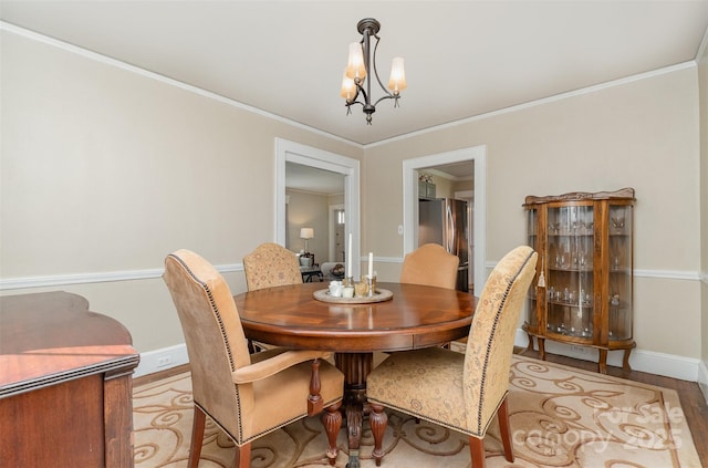 dining area with crown molding, wood finished floors, a notable chandelier, and baseboards
