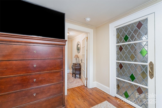 hallway with crown molding, wood finished floors, and baseboards