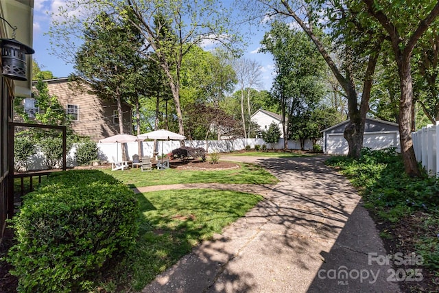 view of yard with a fenced backyard, an outdoor structure, and a garage